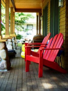 pair of red Adirondack chairs outside on a porch